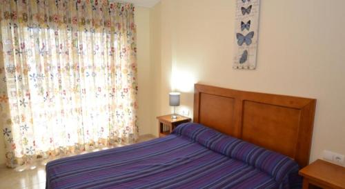 a bedroom with a bed and a large window at Apartamentos Inbesal in La Pineda