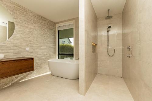 a bathroom with a white tub and a shower at Perfection on Park Lane in Timaru