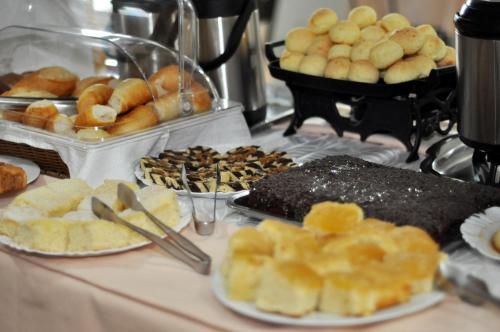 a buffet of pastries and other food on a table at Hotel Carolina 2 - próximo a Universidade de Uberaba uniube - ao Aeroporto Fórum De uberaba - hospital Mario Palmeirio ao Hospital São Marcos e hospital Regional in Uberaba