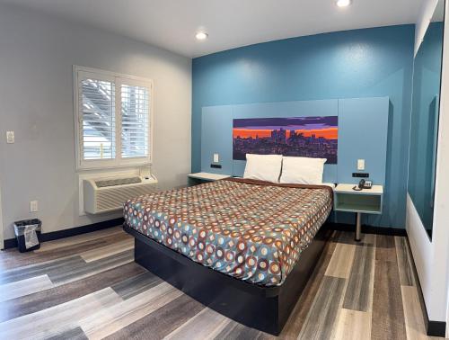 a bedroom with a bed and a blue wall at La Casa Motel, Los Angeles - Burbank Airport in Sun Valley