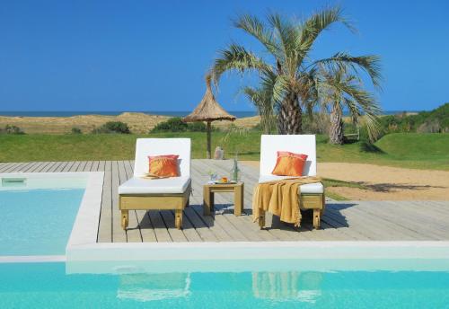 two chairs and a table next to a swimming pool at Casa Suaya in José Ignacio