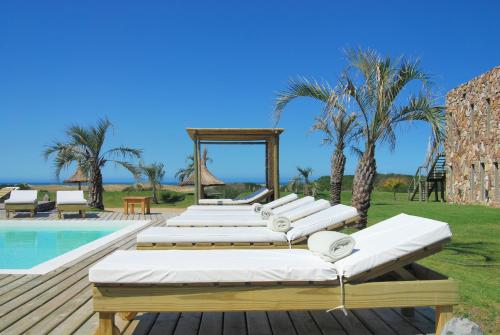 a row of chaise lounge chairs next to a pool at Casa Suaya in José Ignacio