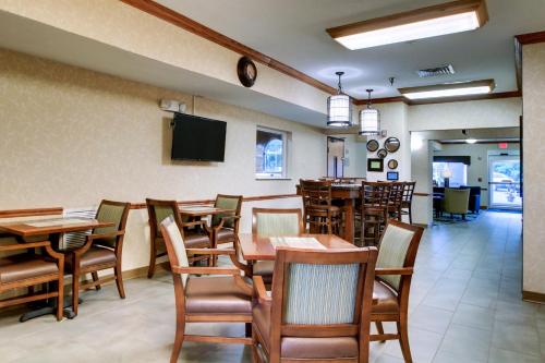 a dining room with tables and chairs and a television at Baymont by Wyndham Galesburg in Galesburg