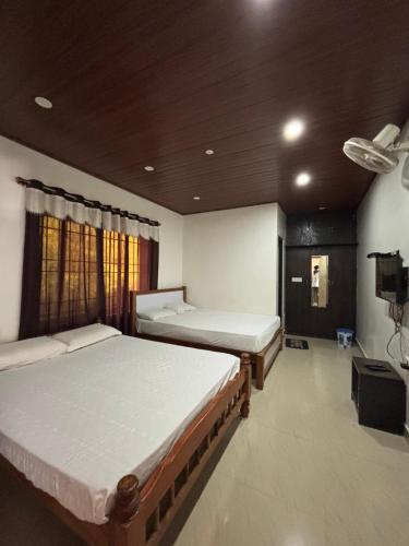 a bedroom with two beds and a window at New Hambala Homestay in Attigundi