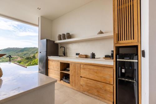 a kitchen with wooden cabinets and a black refrigerator at Yemaya Villas in Kuta Lombok