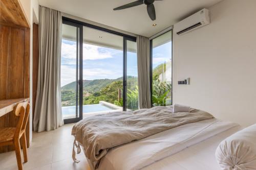 a bedroom with a bed and large glass windows at Yemaya Villas in Kuta Lombok