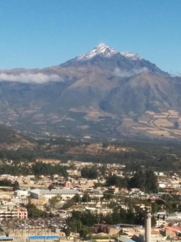 a view of a city with a mountain in the background at Hostal Curiñan in Otavalo