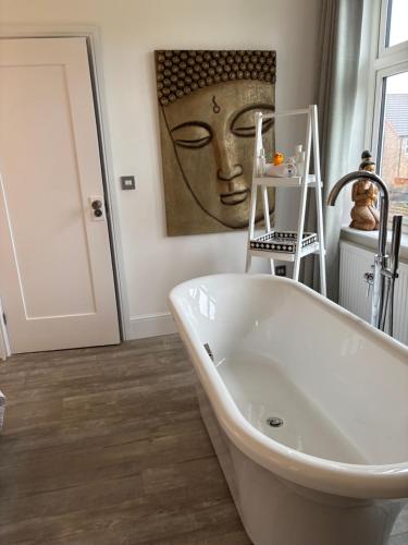 a bathroom with a tub and a painting of a head at Boutique Rooms at The Ellesmere in Hornsea