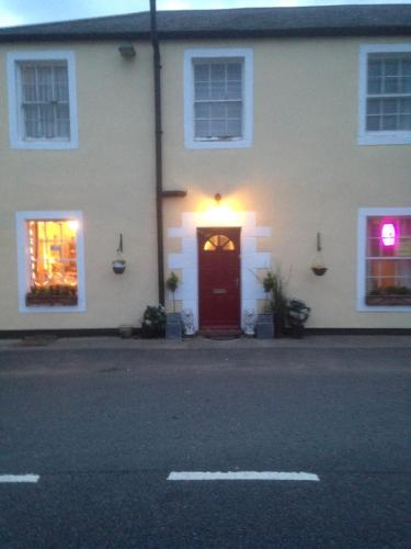 a white house with a red door and a window at Lynebank House Hotel, Bed & Breakfast in Carlisle