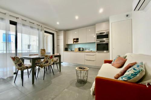 a kitchen and living room with a couch and a table at Villa Marie 2 Appartement tout confort climatisé 1 chambre proche plage in Le Grau-du-Roi
