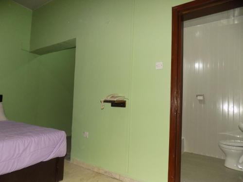 a bathroom with a bed and a toilet in a room at Posh Apartments and Hotel in Ikeja