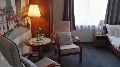 a hotel room with a bed and a chair and a table at Pension Villa Marit in Prague