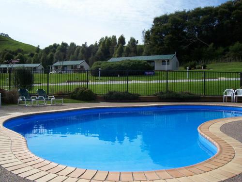 a pool in a backyard with a tennis court at Waitomo TOP 10 Holiday Park in Waitomo Caves