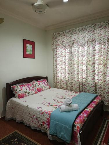 a bedroom with a bed and a window with flowers at HOMESTAY TASNIM in Bentong