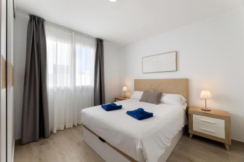 a bedroom with a white bed with blue towels on it at Merlin 14 V1 in Playa Honda