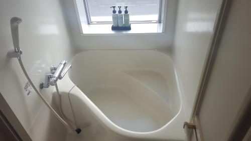 baño blanco con lavabo y ventana en Smile Hotel Shirakawa, en Nishigo