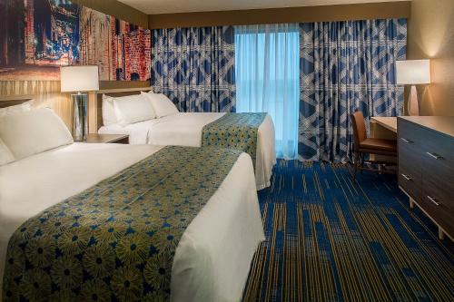 um quarto de hotel com duas camas e uma secretária em HoteLumiere at the Arch em Saint Louis