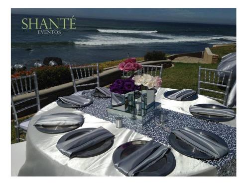 a table with black plates and flowers and the ocean at La Mansión Residency Suites Ensenada in Ensenada