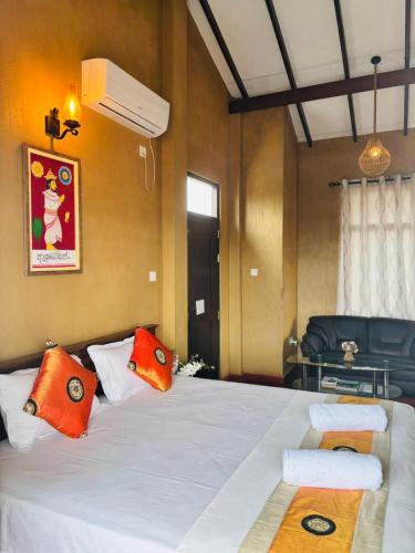 a bedroom with a large white bed with orange pillows at Negombo Green Palace in Negombo