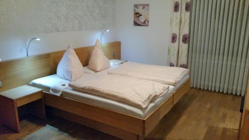 a bed with white sheets and pillows on it at Hotel-Restaurant Fröhlich in Kaiserslautern