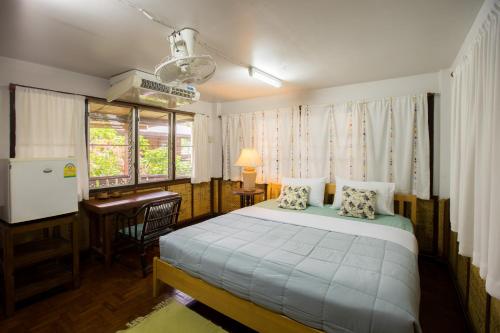 a bedroom with a bed and a desk and a window at Mountain View GuesthouseChiangmai in Chiang Mai