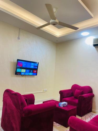 a room with two red chairs and a flat screen tv at AL FANAR REST HOUSE LLC in Ras al Khaimah
