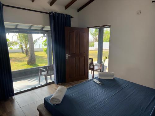 a bedroom with a blue bed and a sliding glass door at Tuktuk Cabanas in Negombo
