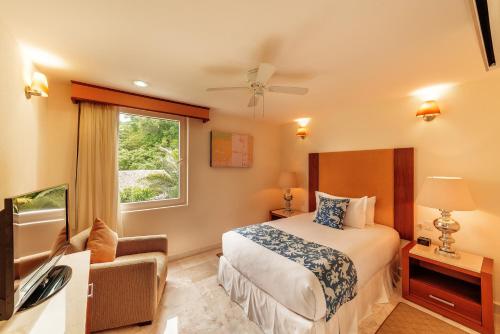 a hotel room with a bed and a television at Grand Miramar All Luxury Suites & Residences in Puerto Vallarta