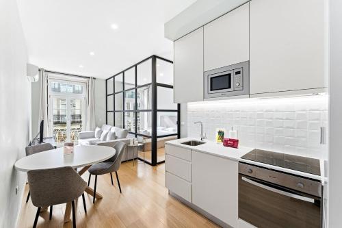 a kitchen with white appliances and a table and chairs at GuestReady - Modern Apartment in Bolhão in Porto