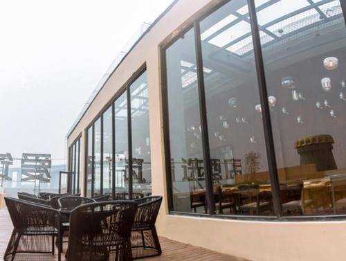 a group of chairs and tables in a building with windows at Aizhu Boutique Theme Hotel in Xiamen