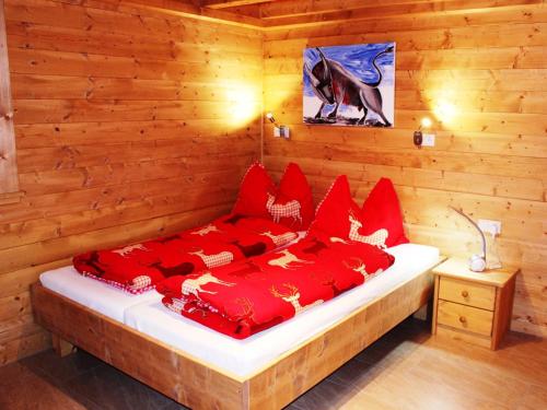 a bed in a wooden room with red pillows at Feriendorf X-Alp Lodges Ötztal in Sautens