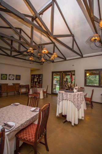 a dining room with two tables and chairs at Hamiltons Lodge & Restaurant in Malelane