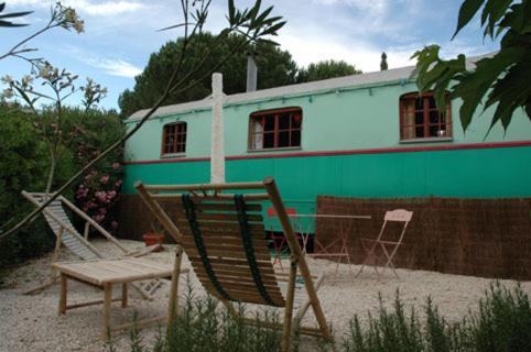 ein grün-weißes Gebäude mit einem Stuhl und einem Haus in der Unterkunft L'Amandari in Plan-de-la-Tour