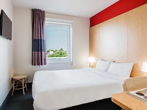 ヴォー・シュル・メールにあるB&B HOTEL Royan La Palmyreの白い大型ベッド1台と窓が備わるホテルルームです。