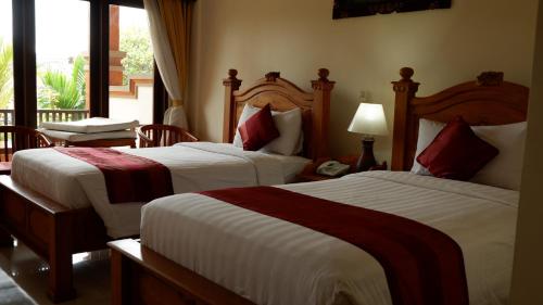 a hotel room with two beds and a window at Swastika Bungalows in Sanur