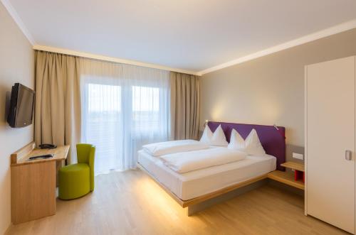 a hotel room with a bed and a window at All in Red Thermenhotel in Lutzmannsburg