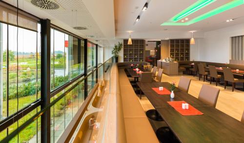 a restaurant with tables and chairs and large windows at All in Red Thermenhotel in Lutzmannsburg