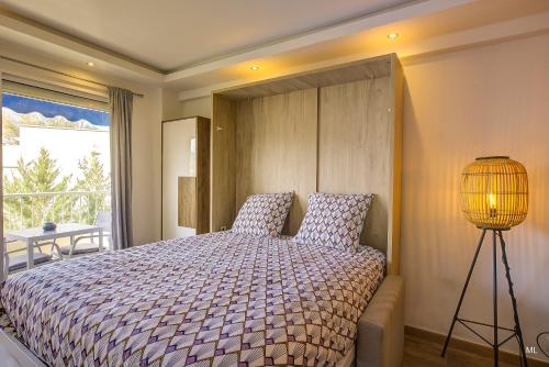 a bedroom with a bed with a lamp and a window at WIlson Palace - Studio avec terrasse et climatisation in Antibes