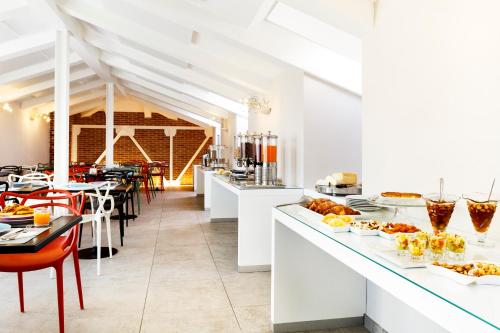 a restaurant with white counters and tables with food at Best Western Plus Royal Superga Hotel in Cuneo