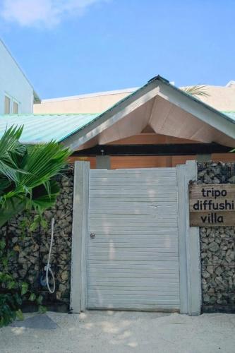 a garage door with a sign in front of a building at Tripo Dhiffushi Villa in Dhiffushi