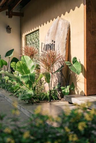 a sign on the side of a building with plants at Lumi Hội An Hotel in Hoi An