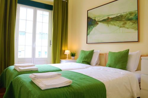 um quarto com 2 camas com lençóis verdes e brancos em Lisbon99 em Lisboa