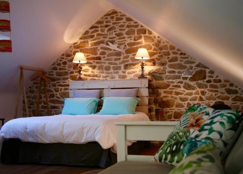 une chambre avec un lit et un mur en pierre dans l'établissement Les chambres du Manoir de Kerhel, à Locoal-Mendon