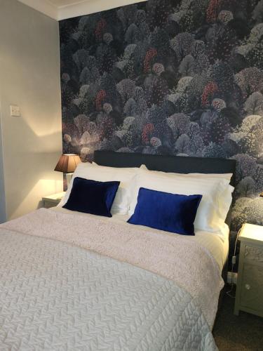 a bedroom with a large bed with blue pillows at Middlethorpe Apartment in York