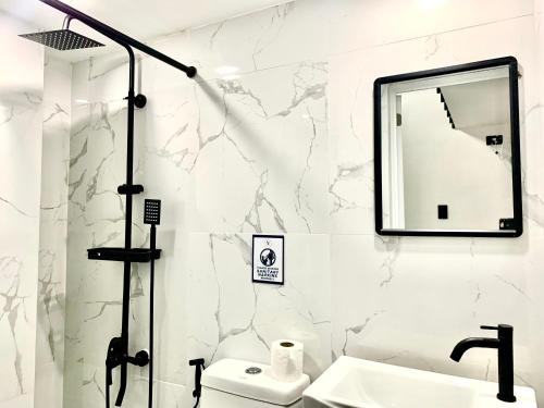 a bathroom with a sink and a mirror and a toilet at Natos Residences - Gonzaga in Bacolod