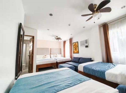 a hotel room with two beds and a couch at Natos Residences - Gonzaga in Bacolod