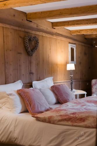 a bed with pillows and a heart on a wall at La Grange aux Coqs in Ittenheim