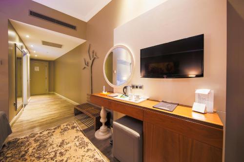 um quarto com uma secretária, uma televisão e um espelho em Doğa Thermal Health & Spa em Pamukkale