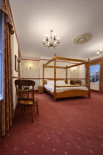 a bedroom with two beds and a chair and a chandelier at The Miners Rest, formerly The Radstock Hotel, near Bath in Radstock