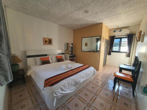 a bedroom with a large white bed and a chair at Forge boutique in Chiang Mai